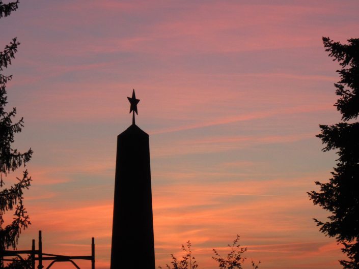 Some monument in Como, Italy with pentagram symbol on top with late evening sky background of reddish orange.