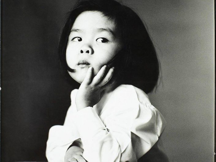 Little asian girl posing in front of camera. Black and white photo by Irving Penn, 1980.