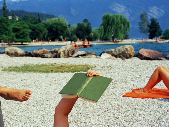 Martin Parr photo of a book held by a lying reader near the Garda lake, Italy, 1999