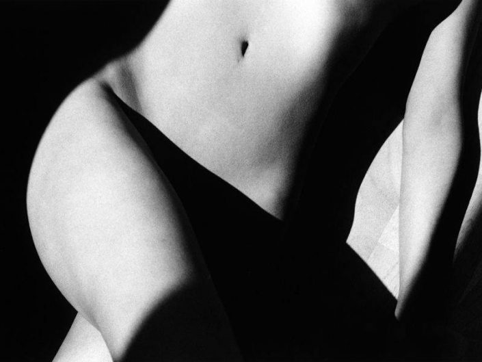 Ralph Gibson semi erotic black and white photo of a female groid hidden in the falling shadow from the leg. Black background