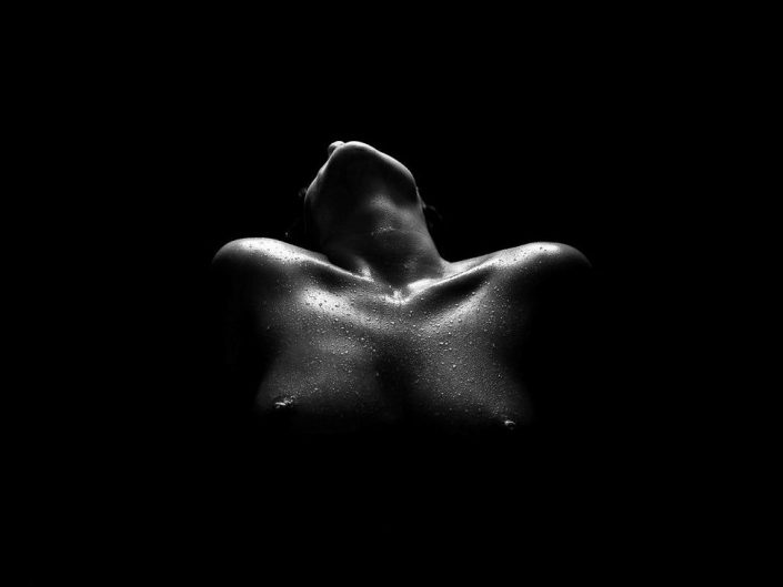 Naked woman in the black background leaning backwards, professional photography by unknown artist