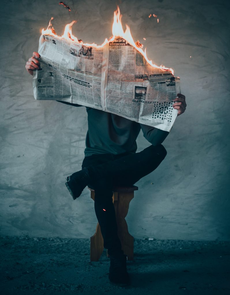 man sitting reading burning newspaper to illustrate microdosing and emotions